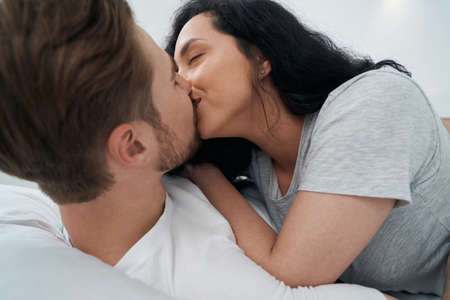Passionate young female kissing male on lips
