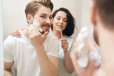 Woman watching her beloved man preparing skin for shaveの写真素材