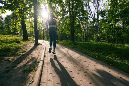 Sporty woman going running in green wood