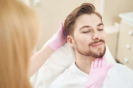 Beauty specialist touching man chin before procedureの写真素材