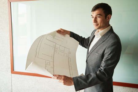 Architect spreading out drawings in his handsの写真素材