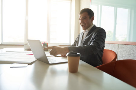 Excited man pointing at laptop display at office desk
