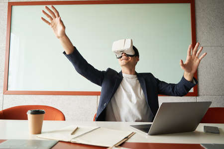 Male white collar worker enjoying VR environment through gogglesの写真素材