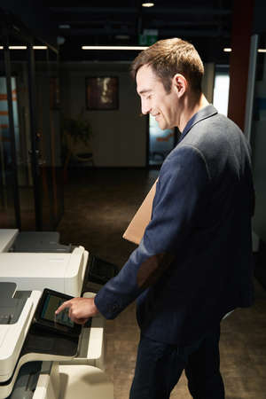 Smiling man choosing settings on office printer