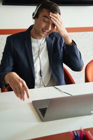 Male clerical worker touching head during online conversationの写真素材