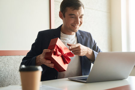 Male pointing to gift box for laptop cameraの写真素材