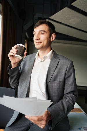 Male drinking coffee at his workplace while keeping papersの写真素材