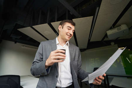 Joyful male with coffee skimming through file in his handの写真素材