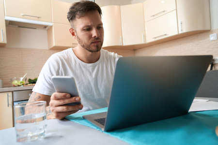 Troubled man working from home with laptop and making call