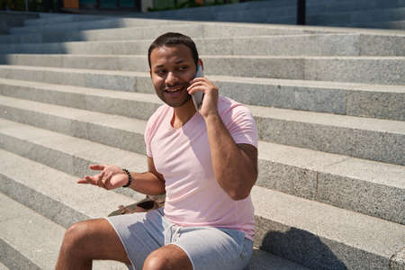 Pleased male person chatting on mobile phone