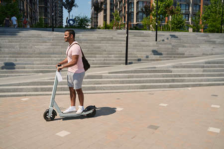 Joyous adult male person enjoying e-scooter trip