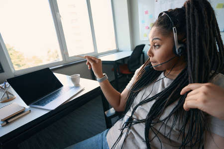 Serious company employee wearing headphones during phone conversation