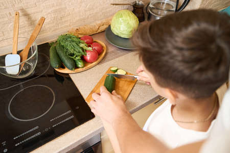Kid slicing cucumber into pieces with parent helpの写真素材