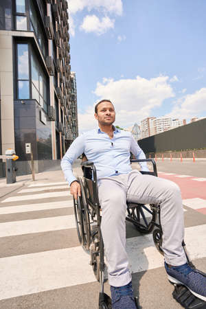 Disabled man seated in wheelchair crossing crosswalk