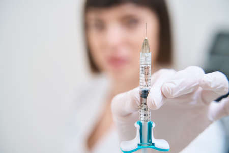 Female doctor showing syringe with liquid for skin tighteningの写真素材