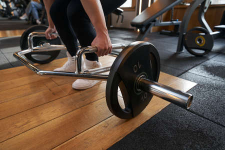 Female bodybuilder doing exercise with plate-loaded trap-bar