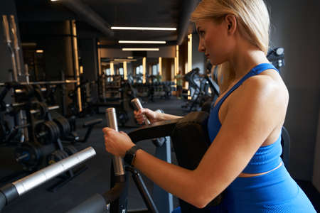 Sporty woman exercising on modern fitness equipment