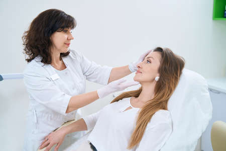 Dermatologist examines the skin of the patient faceの写真素材