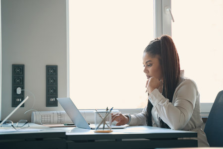 Concentrated young draftswoman working on portable computer