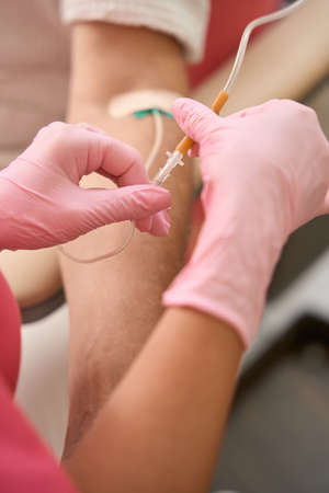 Female hands of nurse hold dropper near the patient handの写真素材
