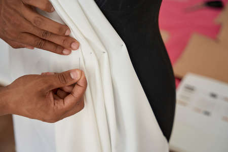 Male fashion designer making female dress in atelier