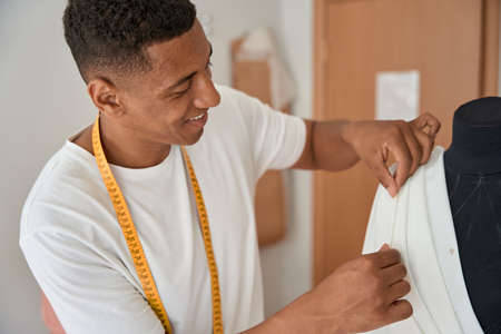 Joyful male fashion designer working with fabrics