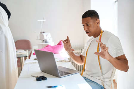 Young fashion designer communicating online at work