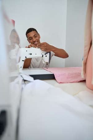 Jolly young man enjoying work in tailor workshopの写真素材