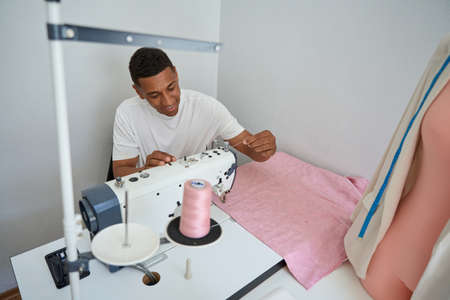 Male tailor using sewing machine at work