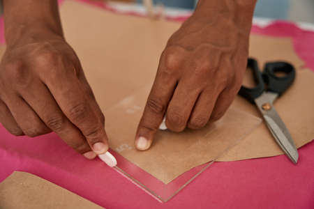 Male tailor making patterns on fabric before sewingの写真素材