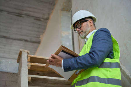 Adult male foreman makes notes in a folder