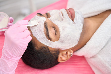 Beautician in nitrile gloves conducting beauty procedure on clientの写真素材
