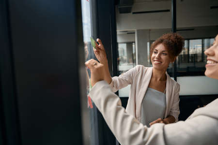 Cropped photo of women peeling stickers from window in officeの写真素材