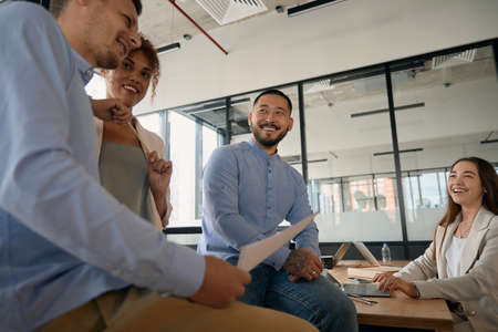 Team of employees chatting and laughing being in open officeの写真素材