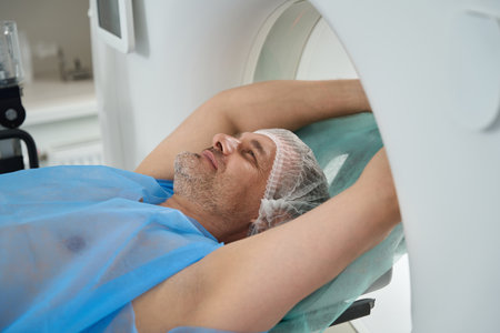 Smiling man with arms outstretched up lies in tomography cameraの写真素材