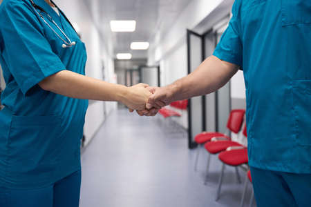 Two doctors shake hands in the coridorの写真素材