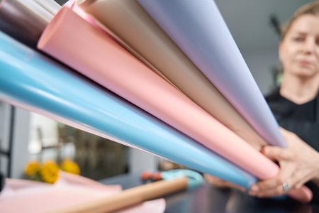 Florist holds lot of multi-colored paper for bouquet of flowers.の写真素材