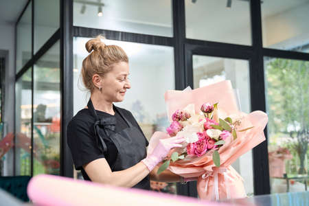 Portrait of woman florist looking at bouquet in flower shopの写真素材