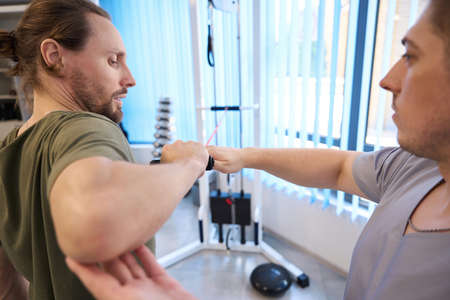 Instructor conducts session of physiotherapy exercises on a power simulatorの写真素材