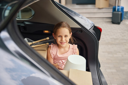 Photo of happy girl in trunk of car with boxesの写真素材