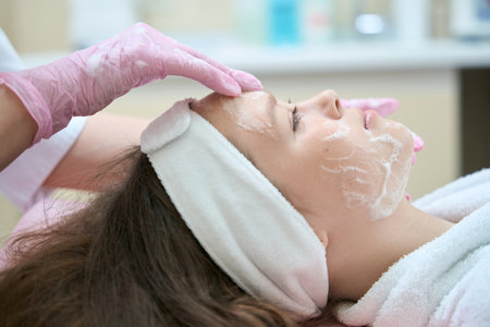 Profile of face of girl being applied cream by beauticianの写真素材