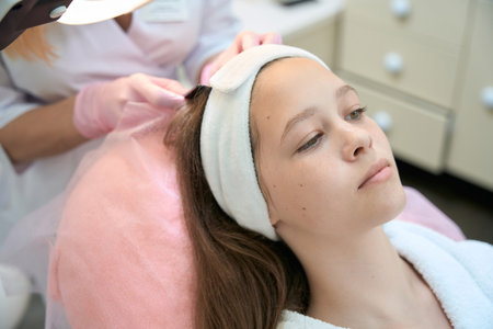 Close-up portrait of female client during hair check at beauticianの写真素材