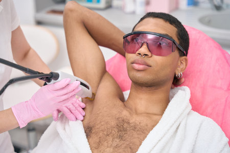 Young man undergoing laser epilation procedure in beauty clinicの写真素材