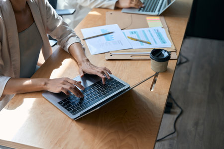 Cropped photo of woman typing on computer in coworking spaceの写真素材