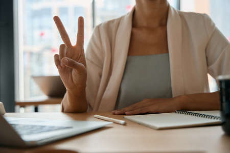 Photo of woman showing fingers sign of success in officeの写真素材