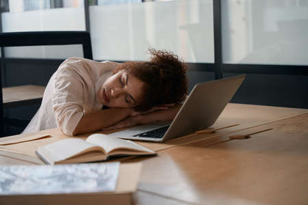 Female employee sleeping with her head resting on her deskの写真素材