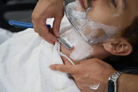 Laid-back gentleman with face covered in foam getting a shaveの写真素材