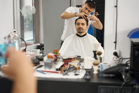 Focused hair stylist taking care of gentleman haircut at salonの写真素材