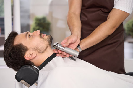Good-looking guy enjoying professional hair trim at barbershopの写真素材