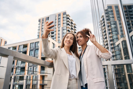 Joyful office employees taking selfies on outdoor balconyの写真素材